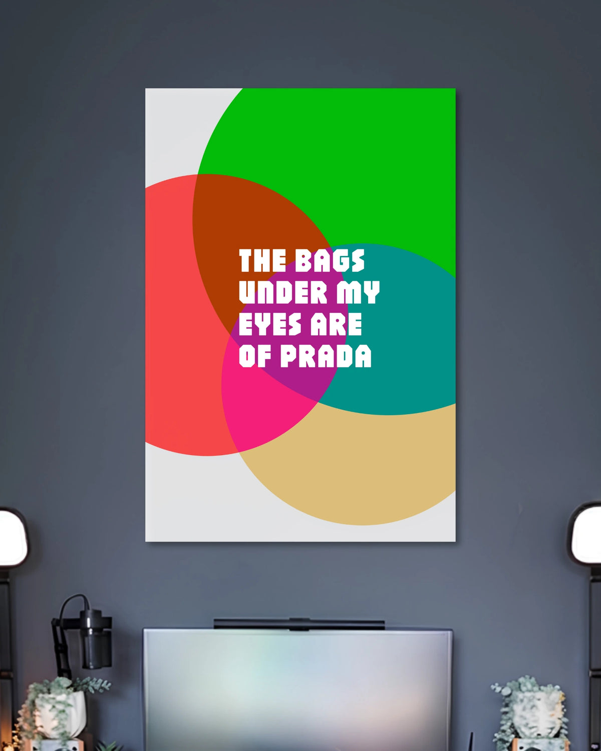 The Bags Under My Eyes Are of Prada Poster poster design: The phrase “The Bags Under My Eyes Are of Prada” takes centre stage in bold white lettering. Overlapping circles in green, red, pink, teal, and beige create a colourful pop art design with a fashion inspired sense of humour.