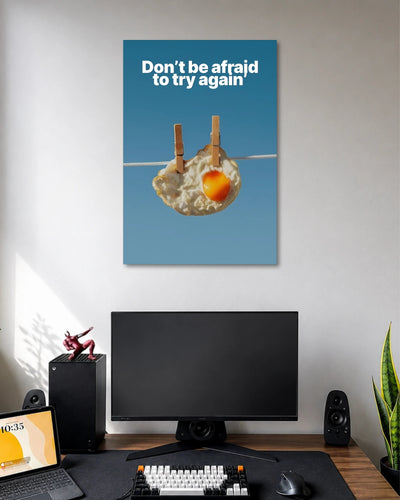 Don't Be Afraid to Try Again Motivational Poster poster design: Featuring a fried egg hanging from a clothesline against a clear blue background, this quirky motivational poster carries the message "Don't be afraid to try again." Its unexpected visual makes encouragement feel playful and memorable.
