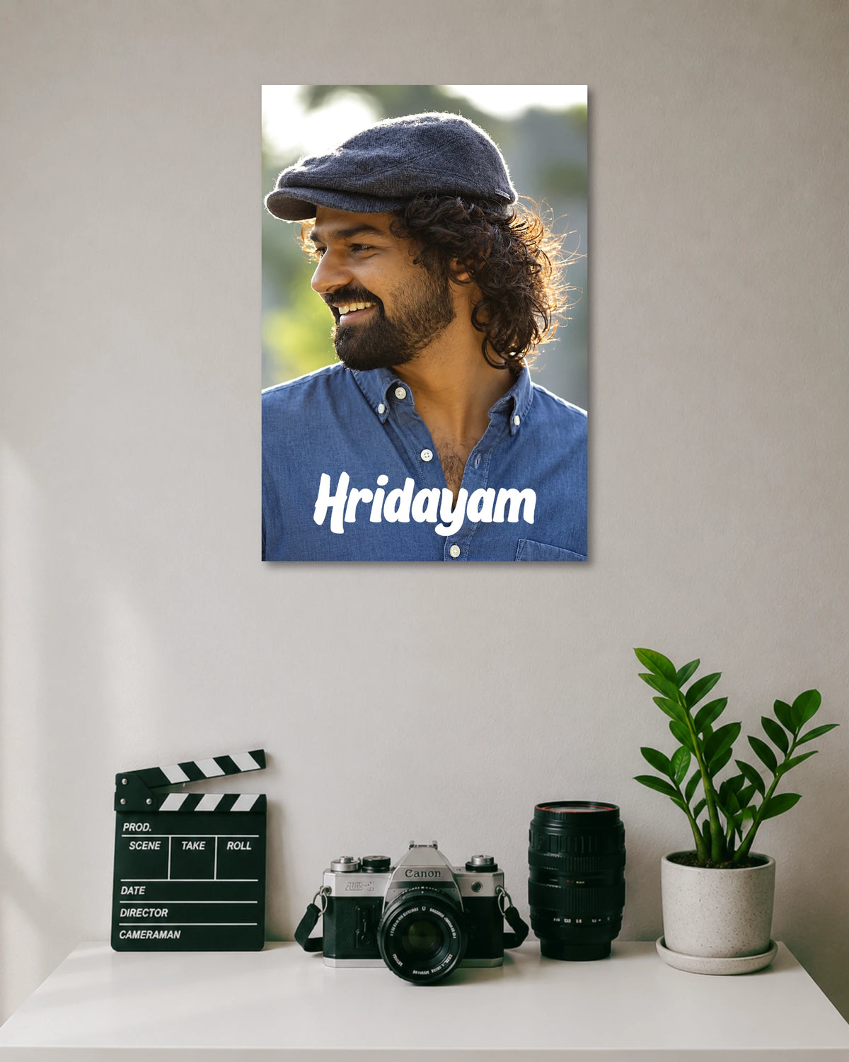 Hridayam Movie Poster Featuring Pranav Mohanlal poster design: Pranav Mohanlal wears a flat cap and blue shirt in this portrait inspired by Hridayam. White lettering across the lower section displays the film title, giving the design a clean, understated look for Malayalam cinema fans.