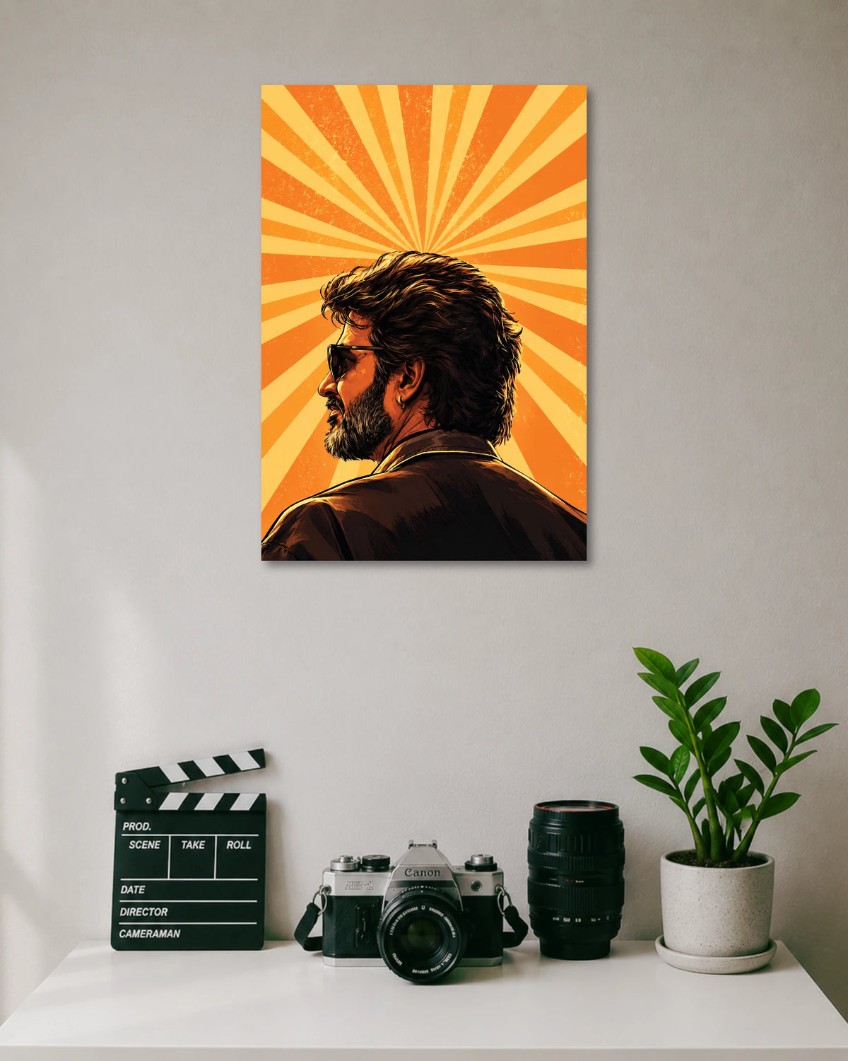 Rajinikanth Orange Sunburst Poster poster design: Rajinikanth appears in side profile wearing sunglasses, a dark jacket and an earring. Radiating orange and yellow sunbeams fill the background, creating a retro inspired composition centred on the iconic Superstar's distinctive look.